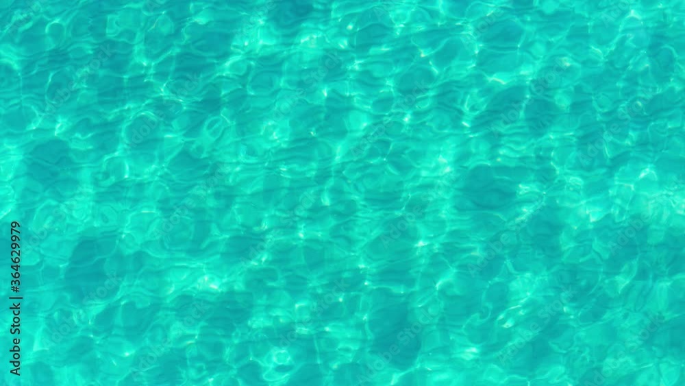 Blue water surface - sand at the bottom of turquoise shallow water - top view on the surface. Purity, vacation, summer holidays concept.