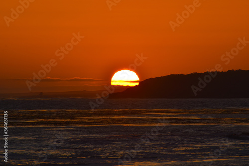 Brilliant red sun setting over ocean waves 