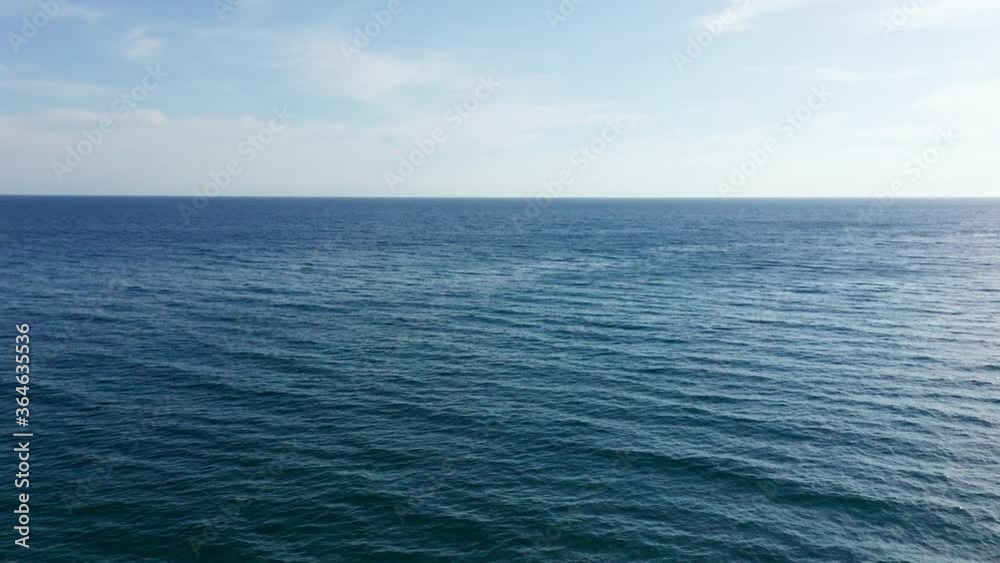 Flying above the dark blue sea toward the horizon, under light blue sky. Aerial footage. Flying above the dark blue sea toward the horizon, under light blue sky. Aerial footage.