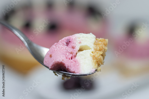 A piece of Cherry cheesecake on tea spoon.