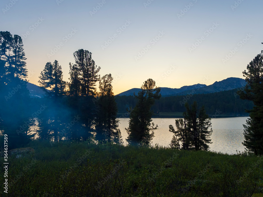 Evening on the forest lake. Darkness descends on a tourist camp. Night in the wild