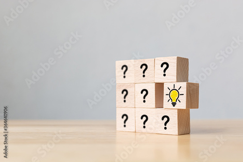Conceptual of creative idea and innovation. Wooden cube block with head human symbol and light bulb icon different question mark symbol