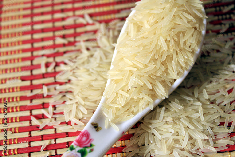 Rice grains in a white plastic spoon on multi color texture background. Macro background of white rice. Basmati rice on a pile isolated on colorful pattern background. Rice grains in a white plastic spoon on multi color texture background. Macro background of white rice. Basmati rice on a pile isolated on colorful pattern background.