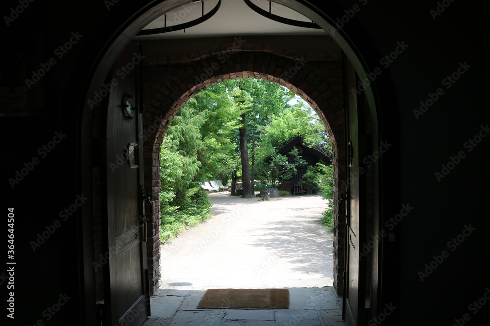 古風な洋風な家の室内から玄関の大きな扉から見た風景