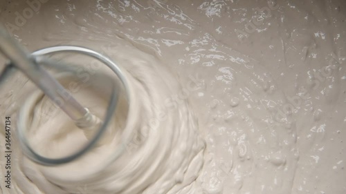 Slow motion pan shot of mixing concrete plaster with electric mixer. spatula and bucket with mortar on the construction site.
