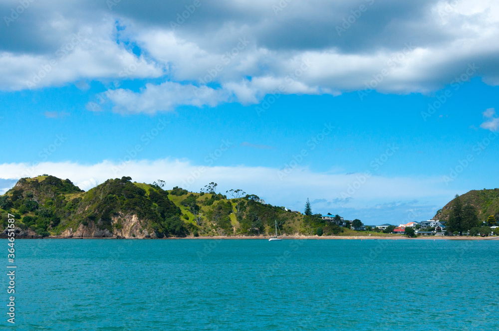 Beautiful seascape, Bay of Islands near Paihia, New Zealand, Cliffs, rocks and mountains in clear turquoise water of the sea and clouds in the sky