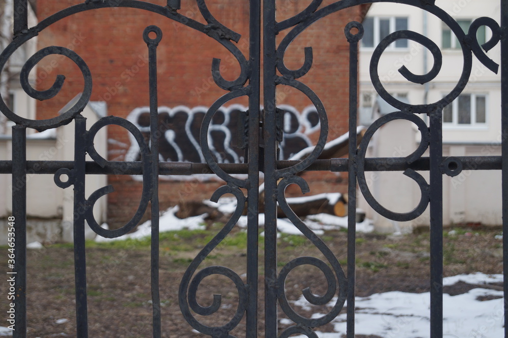 Photo of an iron grating against the background of a poor quarter and outbuildings. Photo of an iron grating against the background of a poor quarter and outbuildings.