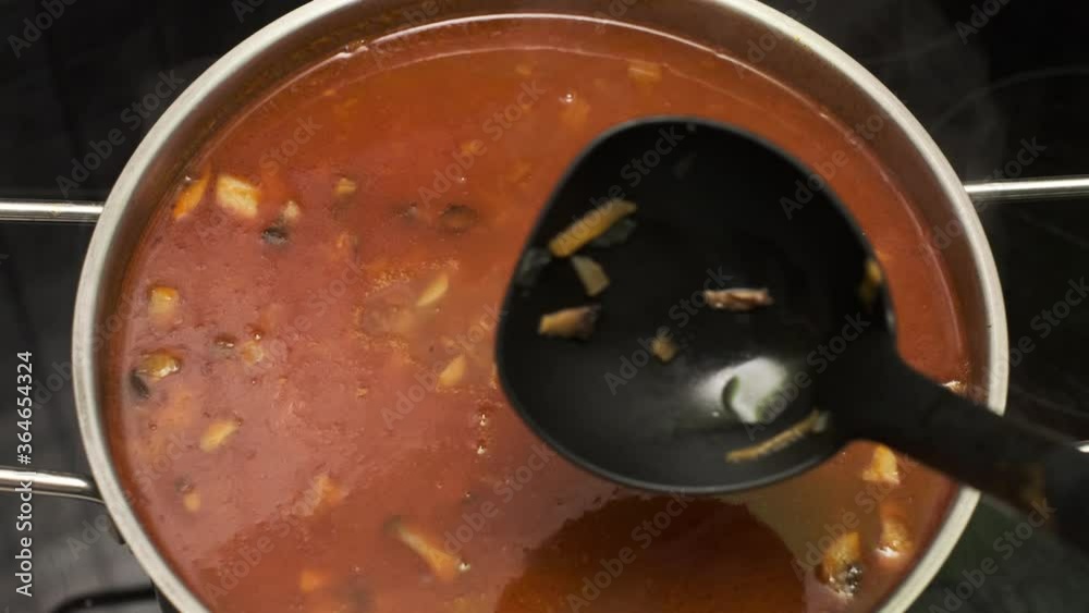 Shef Cooks and mixing Healthy vegetable tomato soup food in bowl in kitchen. Close up POV