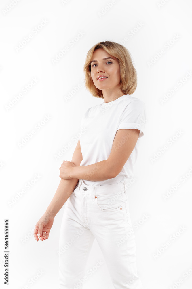 Beautiful young blonde woman in casual white outfit posing over white background. Beautiful young blonde woman in casual white outfit posing over white background.