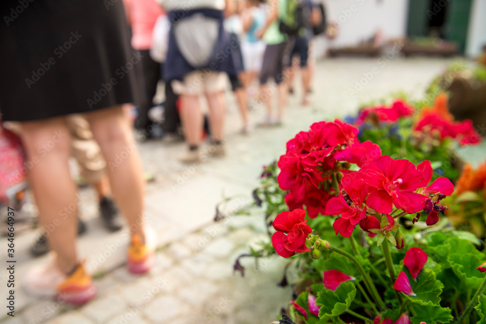 Naklejka premium Group of people standing in line in a hot summer, waiting for the arrival of the train, the bus, the cable car.