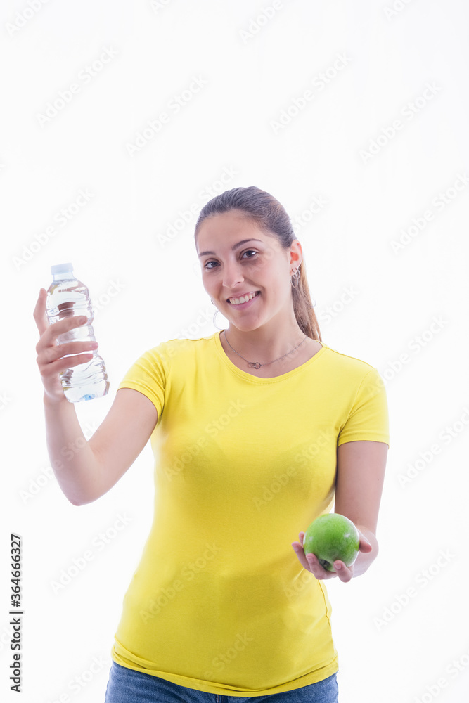 young woman holding a delicious green apple and a bottle of water while smiling at the camera. young woman holding a delicious green apple and a bottle of water while smiling at the camera.