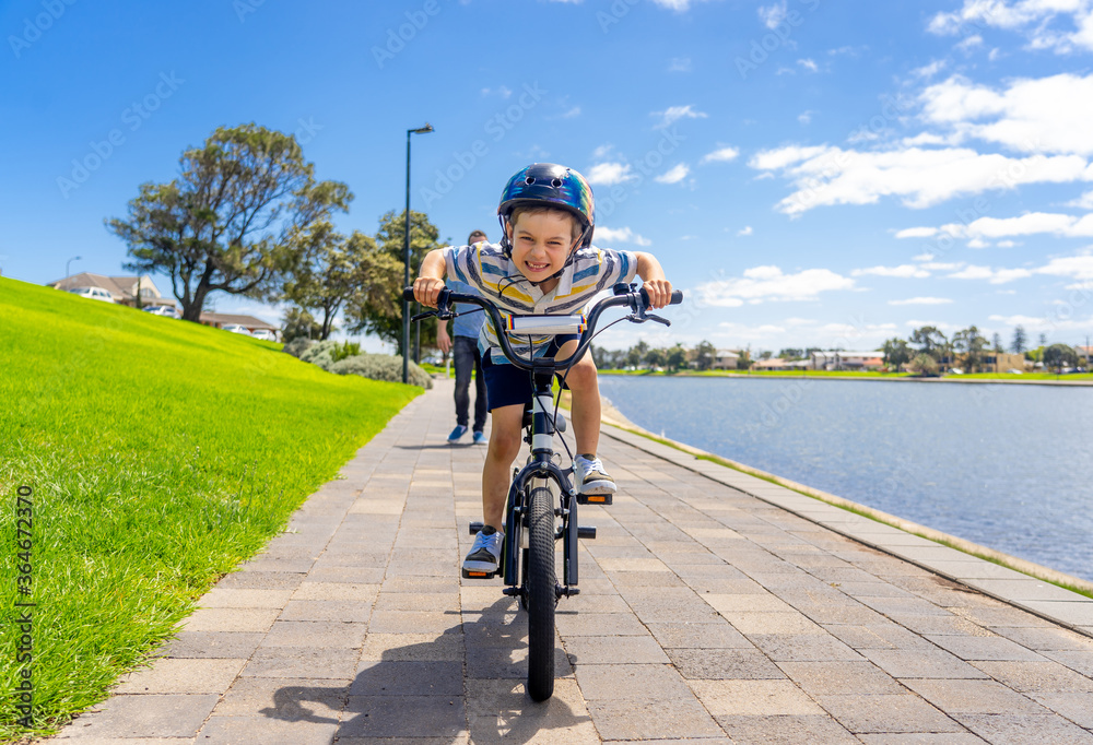 Obraz premium Father teaching his son to ride a bike and having fun together at the park