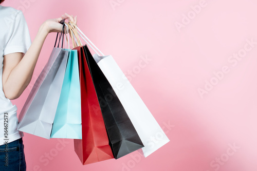 Happy women carrying summer shopping bagsม, isolated on pink background.