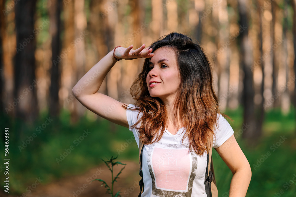Portrait of a woman with long hair and backpacks Hiking in a pine forest, tourism and banner for healthy recreation, copy space Portrait of a woman with long hair and backpacks Hiking in a pine forest, tourism and banner for healthy recreation, copy space