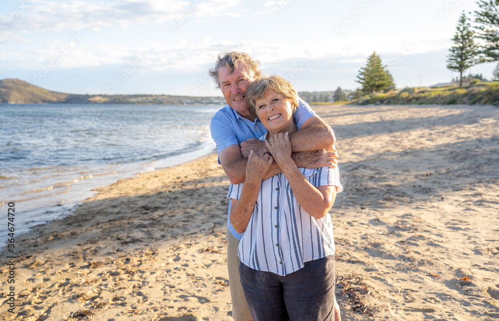 Portrait of happy senior couple at an empty remote beautiful beach on sunny day Portrait of happy senior couple at an empty remote beautiful beach on sunny day