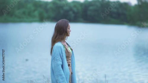 Young beautiful girl walks along the river coast