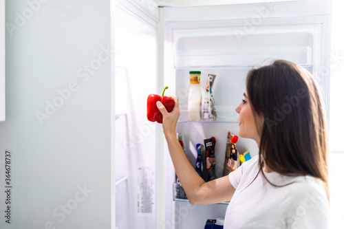 Healthy Eating Concept. Diet. Beautiful young woman near the fridge with healthy food. Fruits and vegetables in the refrigerator. Vegan food