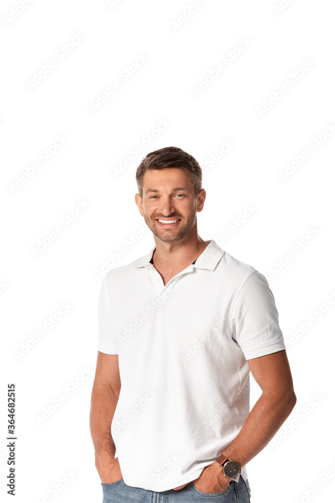 cheerful man in white t-shirt smiling while standing with hands in pockets isolated on white