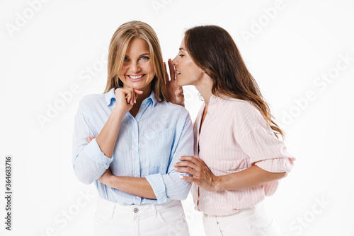 Image of nice brunette woman whispering secret to smiling blonde friend