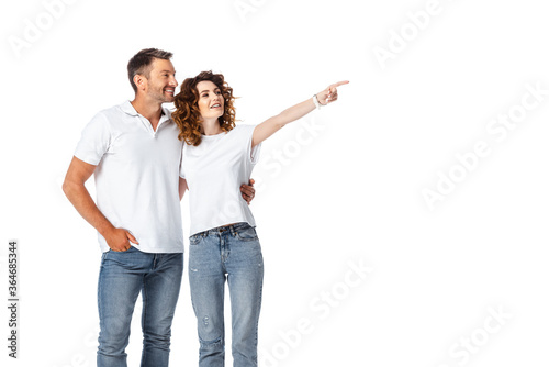 happy woman pointing with finger near cheerful man standing with hand in pocket isolated on white