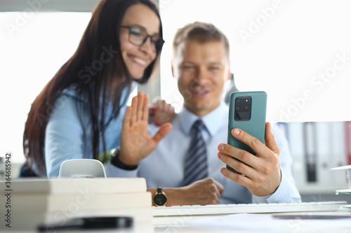 Man and woman are smiling and greeting is waving to interlocutor in a smartphone. Online communication concept