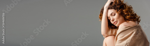 horizontal concept of curly woman with closed eyes touching hair isolated on grey