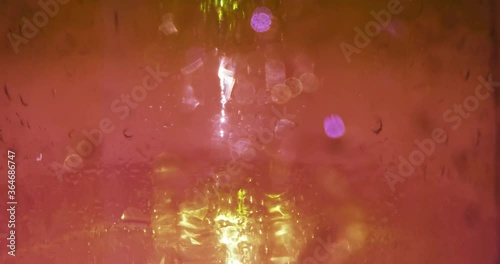 Water drops on crimson pink, dirty red glass, blurred background. Texture