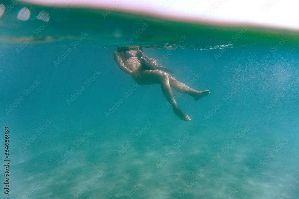 Young woman snorkeling in the sea. Underwater photography of a girl using long fins under the sea.
