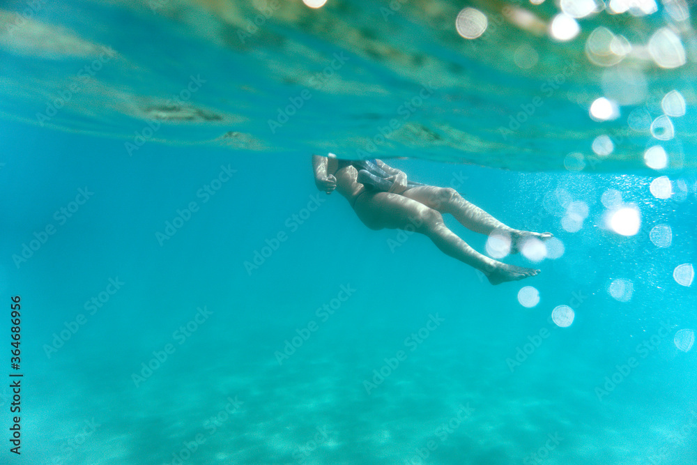 Young woman snorkeling in the sea. Underwater photography of a girl using long fins under the sea.