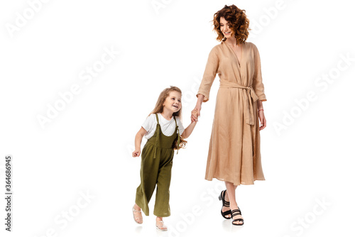 cheerful mother and daughter holding hands isolated on white