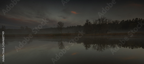 Foggy sunset over lake in forest