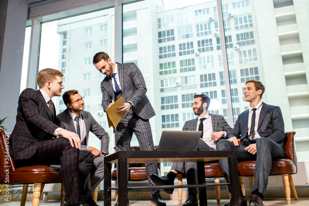 togetherness and partnership of young caucasian business men at work, group of men in tuxedo isolated in modern office, gathered to have discussion, conversation