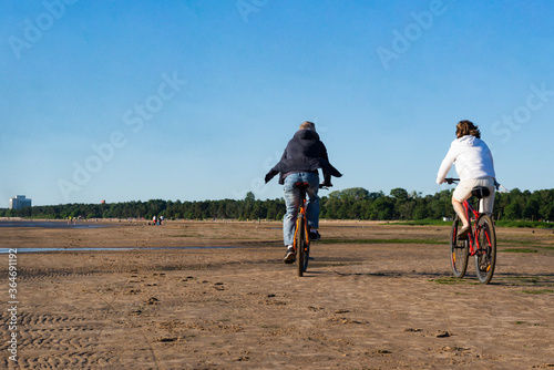  people ride bicycles on the sand on the beach, North coast