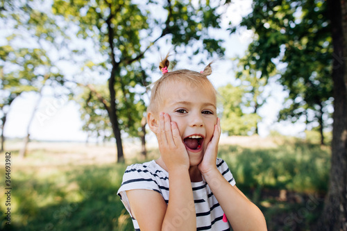 A child screams with happiness and surprise in a summer park outdoors. Happy moments