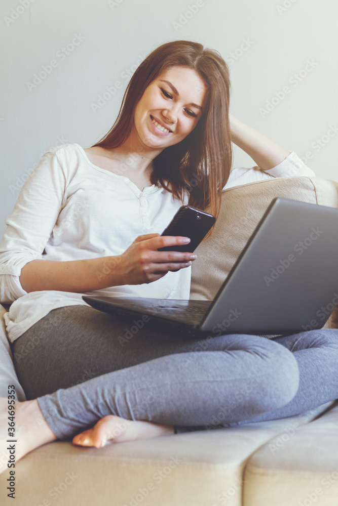 Woman lying on a sofa at home and holding in hand a smart phone. Woman lying on a sofa at home and holding in hand a smart phone.