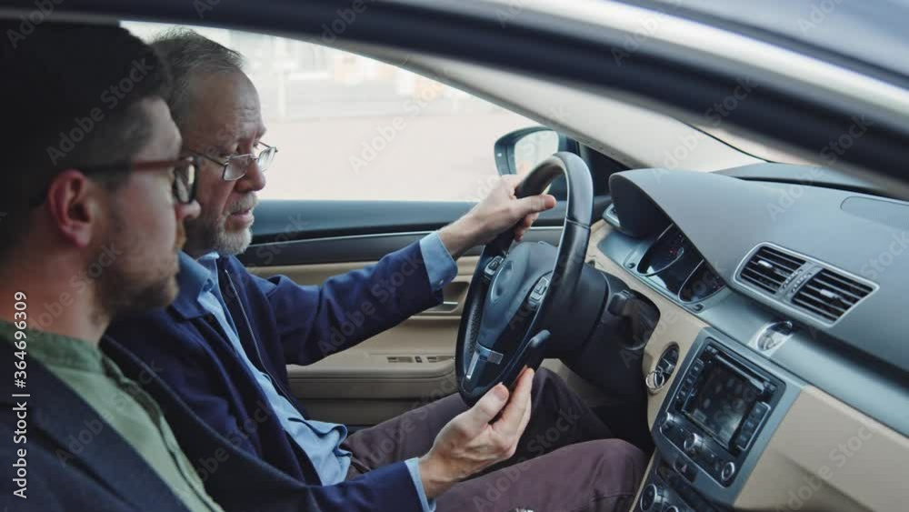 Old caucasian man pensioner learning to drive car with help of instructor and using smartphone navigating gps app on roadtrip. Driver license test. Technology. Business. Old caucasian man pensioner learning to drive car with help of instructor and using smartphone navigating gps app on roadtrip. Driver license test. Technology. Business.