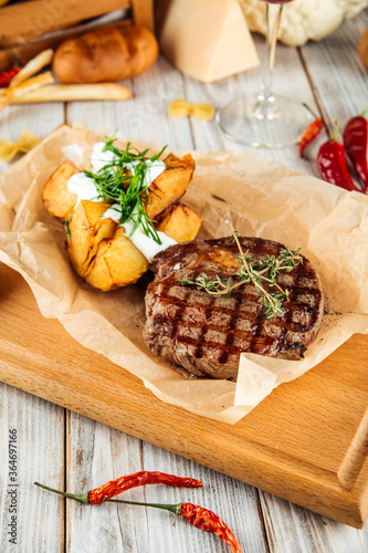 Ribeye beef steak with baked potatoes sour cream