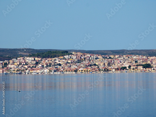 Sardinia view of Sant'Antioco from the lagoon, in the foreground some seagulls float on the calm waters of the lagoon, in the background the village.