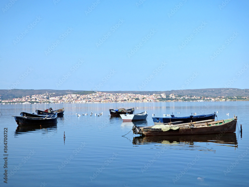 Sardinia view of Sant'Antioco from the lagoon, in the foreground boats typical for fishing in the lagoon, above Sardinia view of Sant'Antioco from the lagoon, in the foreground boats typical for fishing in the lagoon, above