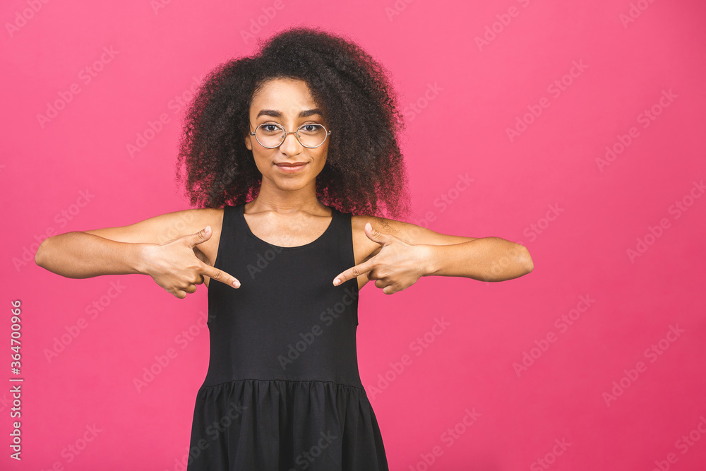 Portrait of a happy young african american woman pointing fingers down at copy space isolated over pink background. Portrait of a happy young african american woman pointing fingers down at copy space isolated over pink background.