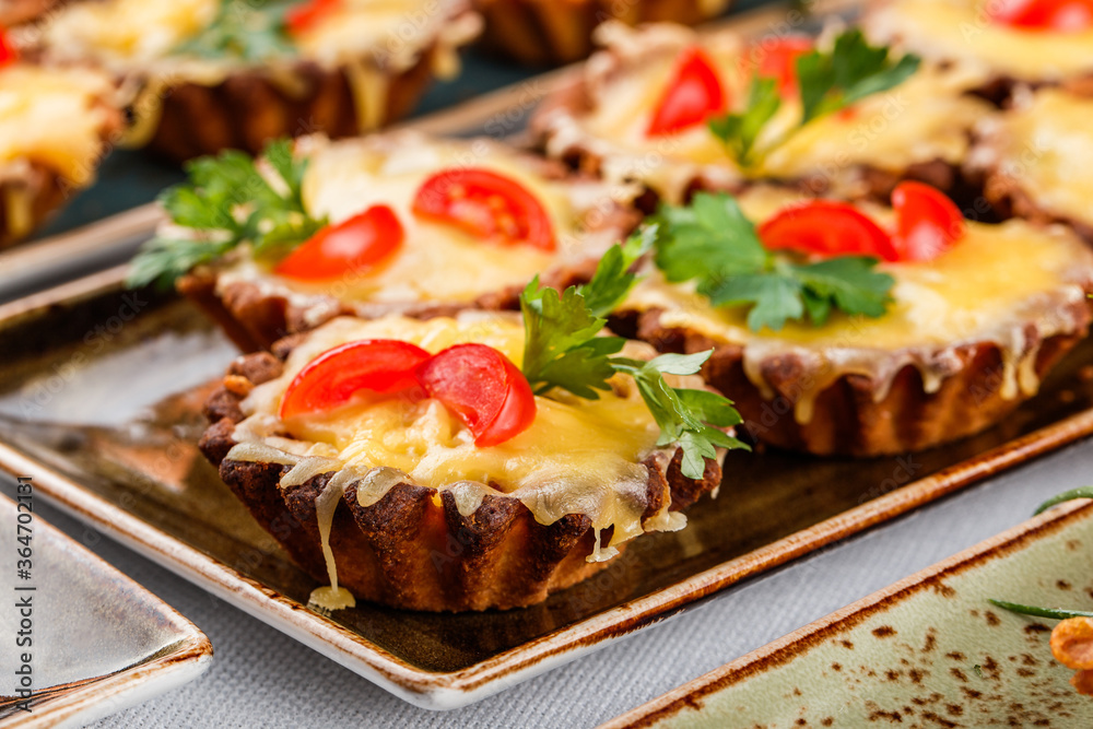Delicious appetizers in tart with cheese and meat in plate on banquet table. Catering food, canape and snacks, close up Delicious appetizers in tart with cheese and meat in plate on banquet table. Catering food, canape and snacks, close up