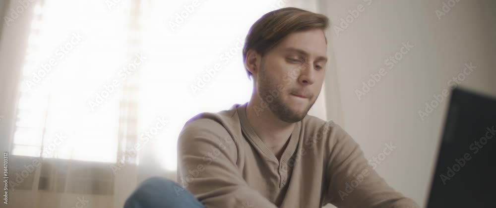 A close up of a young man sitting in bed and working on a computer. Slow motion, BMPCC 4K A close up of a young man sitting in bed and working on a computer. Slow motion, BMPCC 4K