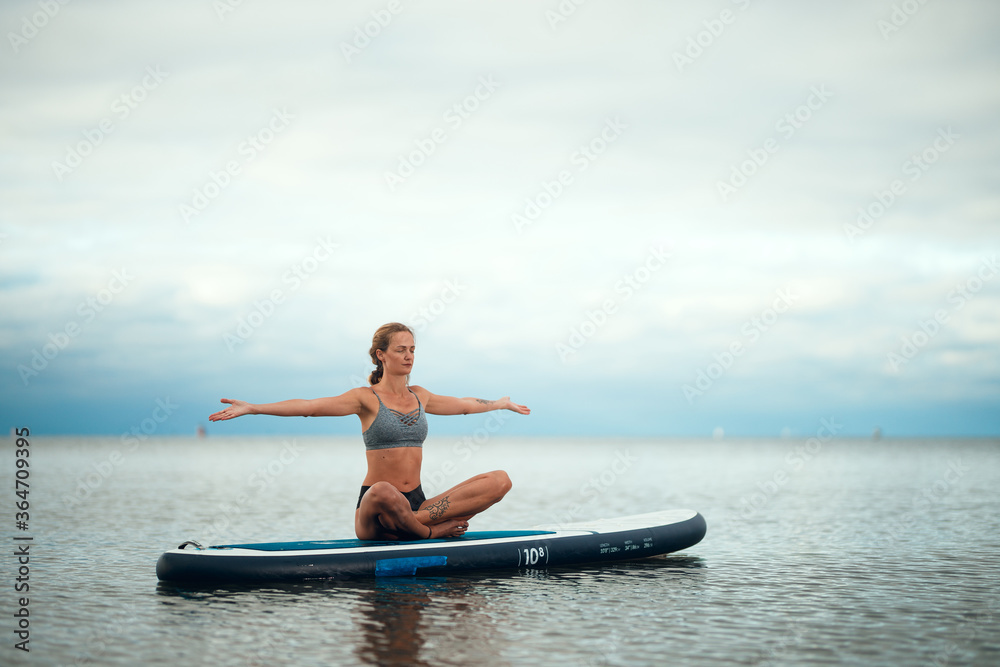 Woman practicing yoga on the paddle board in the morning Woman practicing yoga on the paddle board in the morning