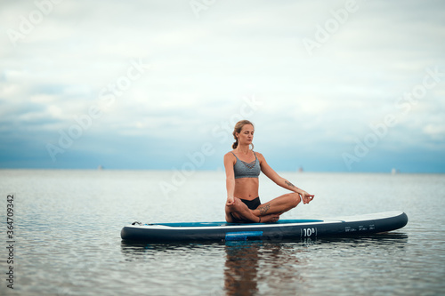 Woman practicing yoga on the paddle board in the morning