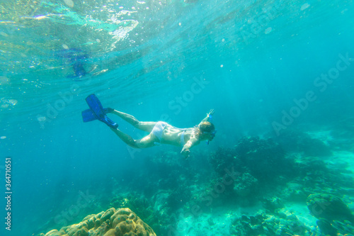 Woman swimming deep in coral reef Andaman Sea of Surin Islands. Ko Surin Marine National Park, underwater scene. Watersport activity in Phuket north, Phang Nga in Thailand.