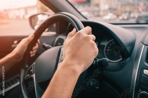 driver keeps his hands firmly on the steering wheel in his car. The concept of learning to drive and safe on the road © EdNurg