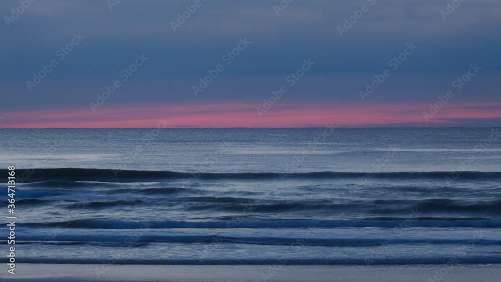 Pose longue créant un effet de filé sur les vagues, pendant l'heure bleue