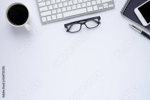 Top view above of White office desk table with keyboard, notebook and coffee cup with equipment other office supplies. Business and finance concept.