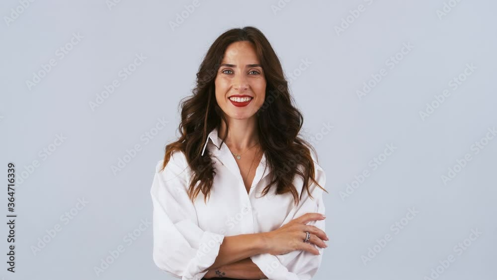 Brunette female in white shirt is looking happy, smiling and showing okay sign while posing against gray studio background. Close up Brunette female in white shirt is looking happy, smiling and showing okay sign while posing against gray studio background. Close up