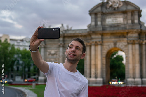 Madrid, Spain / July 13 2020 / Photo of an attractive guy next to Alcala gate in Madrid during sunset	
